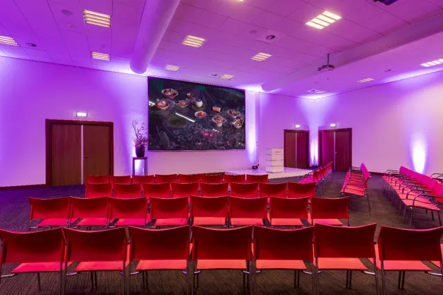 De zaal van Miele Vianen met rode stoelen en paarse verlichting.
