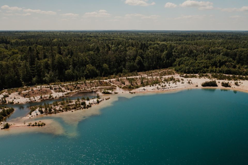 Het blauwe water, het strand en het bos bij het Gasselterveld op een zomerse dag vanuit de lucht.