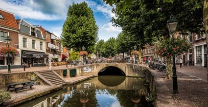 Stadscentrum Oudewater in het Groene Hart, historische binnenstad met gracht, stenen boogbrug, monumentale gevels, winkelstraat en terrassen langs het water.