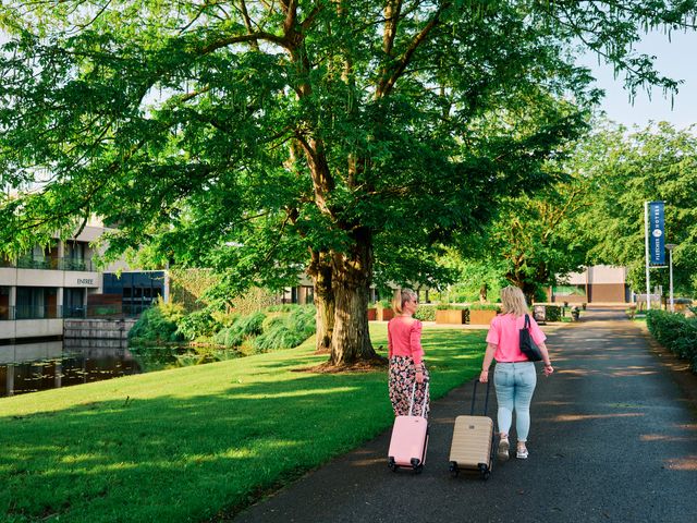 Twee vrouwen lopen met koffers naar de ingang van een hotel