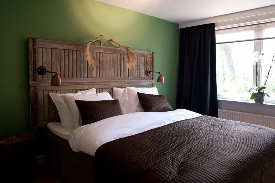 Hotelkamer met groot bed tegen een groene achterwand.