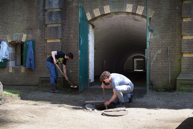 Twee vrijwilligers zijn bezig met het onderhoud van Fort Rijnauwen.
