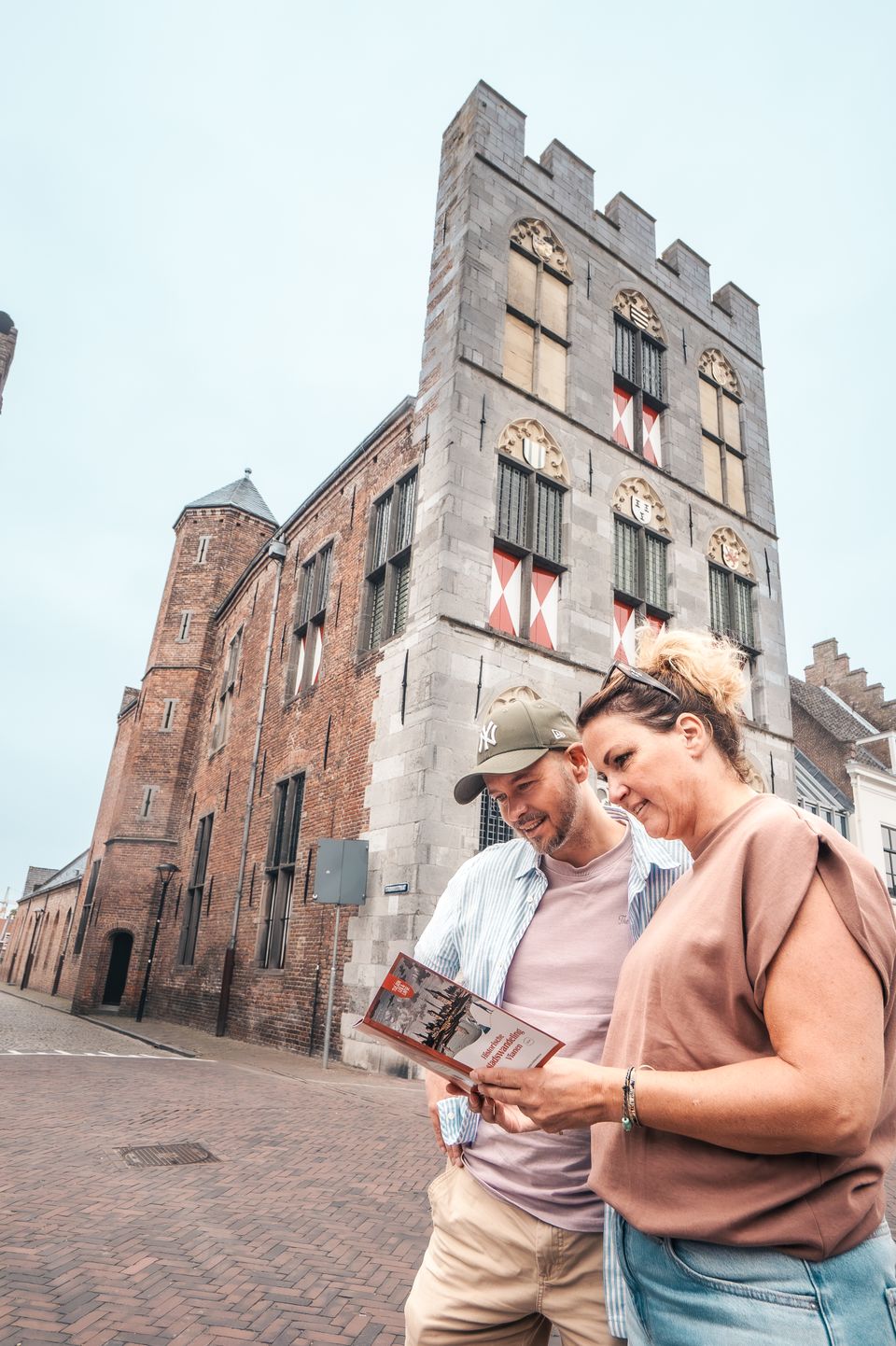 Een man en een vrouw staan voor het stadhuis in Vianen en kijken in een folder.