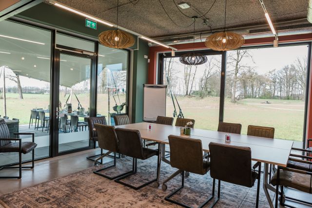 Moderne vergaderruimte bij de Grebbe Lounge met grote ramen en uitzicht op het omliggende landschap. De foto laat de mogelijkheden voor vergaderen en zakelijke bijeenkomsten bij het Grebbelinie Bezoekerscentrum zien.