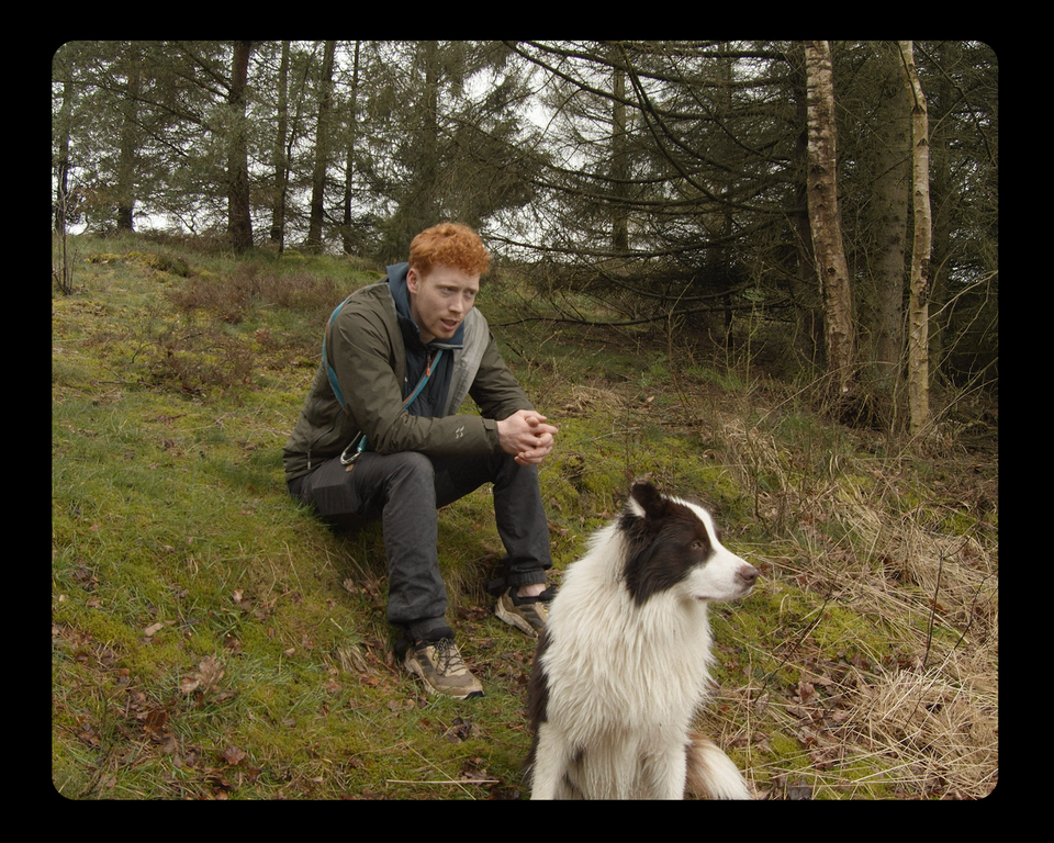 Jongeman met hond zit in een natuurgebied