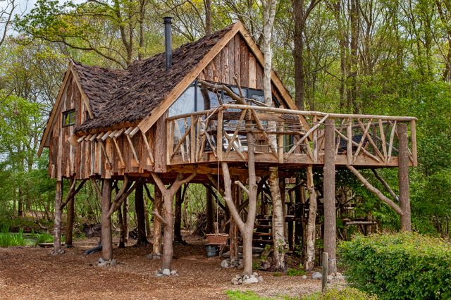 Een grote houten boomhut in het bos.