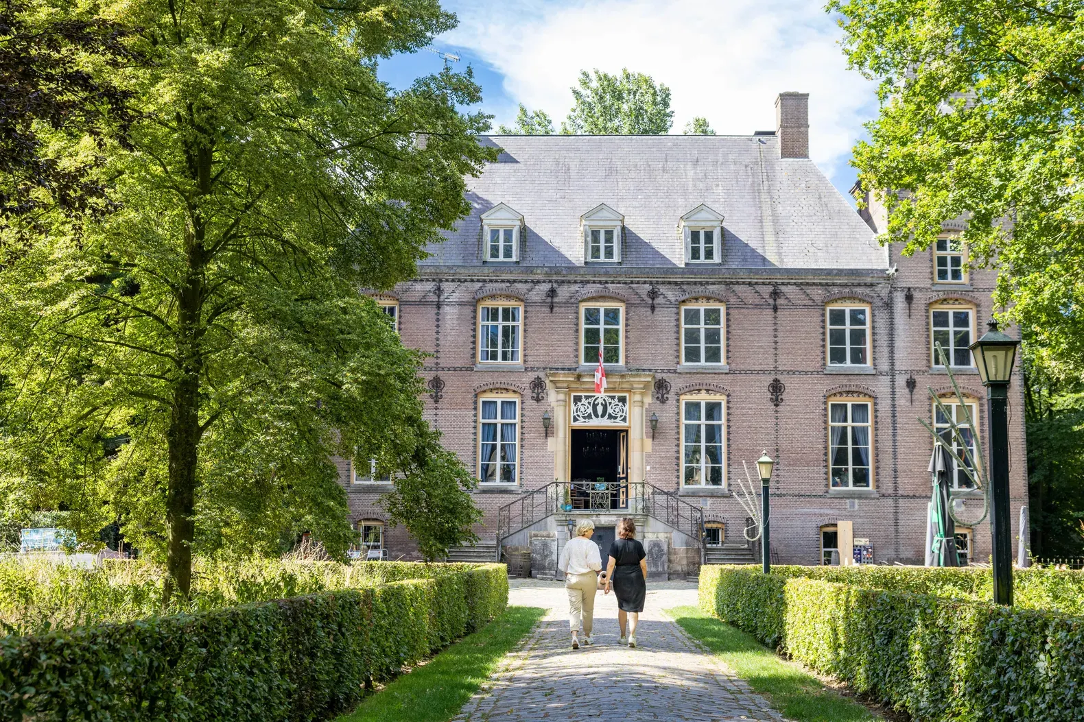 Twee wandelaars lopen op de oprijlaan van Kasteel Nemerlaer Haaren