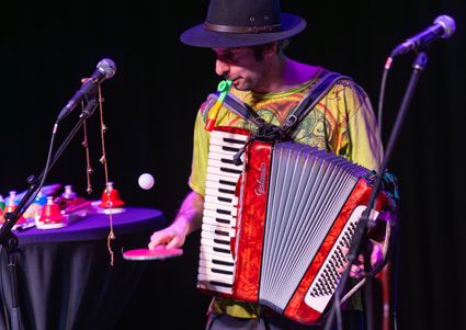 Muzikant met accordeon tijdens een vrolijk optreden in het Groene Hart, terwijl hij tegelijk een pingpongbal hooghoudt met een batje.