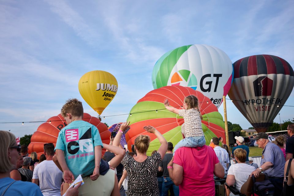 Kinderen kijken op de schouders van hun ouders naar de ballonen tijdens de ballonfeesten van Joure
