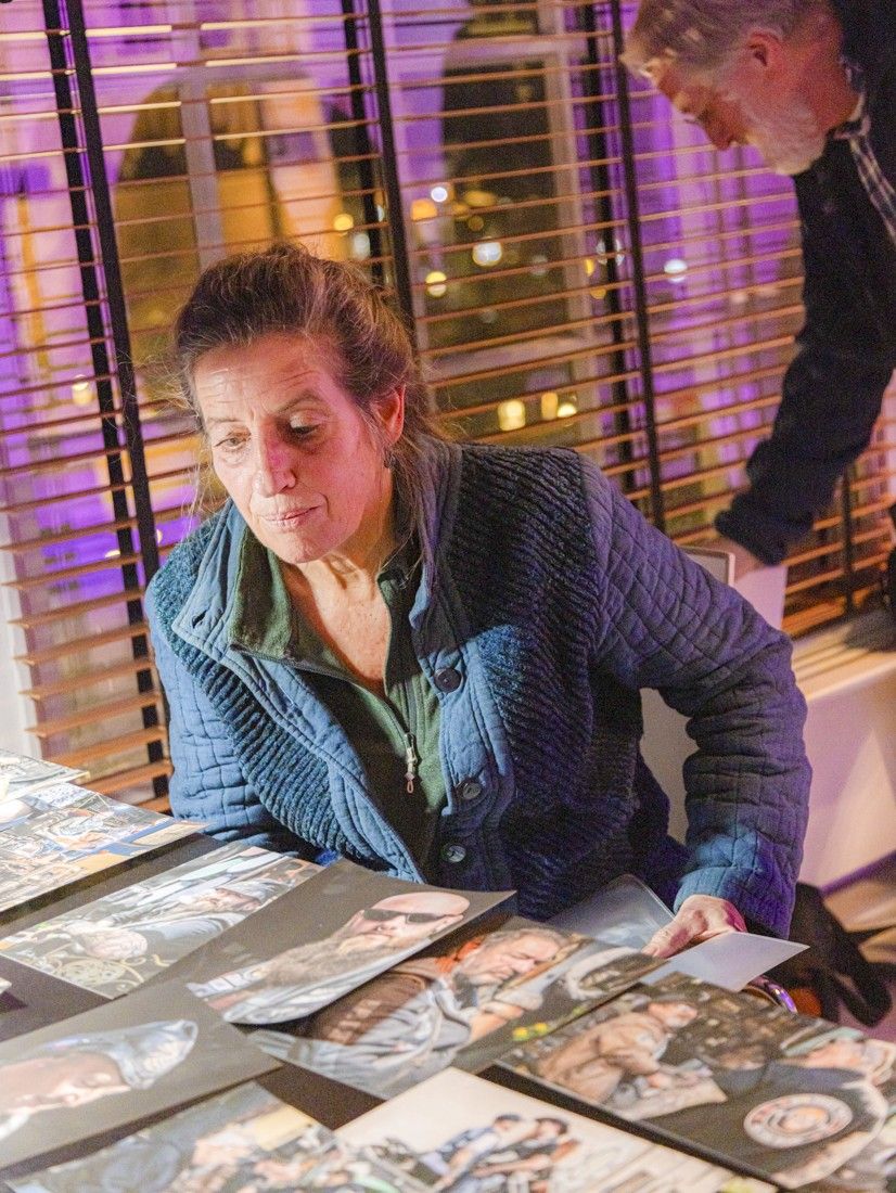 Fototentoonstelling Café Woerden Fotografen, bezoeker bekijkt fotowerk op tafel in Woerden, Groene Hart, binnenlocatie met gepresenteerde portretfoto’s tijdens een culturele fotografieavond.