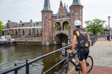 een meneer met een fiets die kijkt naar de waterpoort in sneek