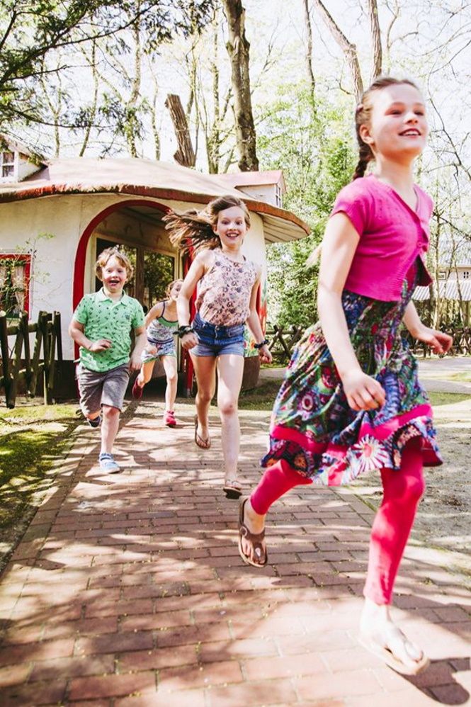 Kinderen komen uit een paddenstoelhuisje gerend.