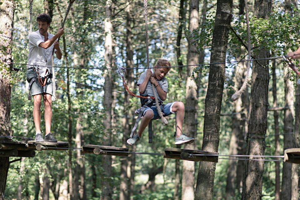 Vater und Sohn schwingen im Kletterpark von Plattform zu Plattform.