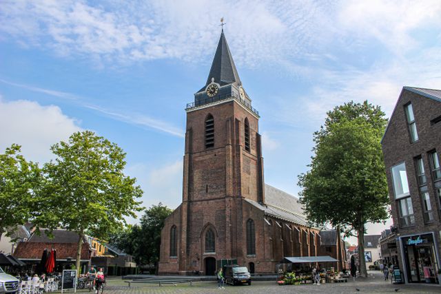 De Petrustoren op het Kerkplein in Woerden met terrassen en marktkraampjes op een zonnige dag.