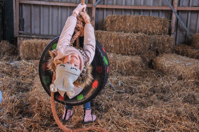 Activiteitenboerderij De Boerinn in Kamerik, Groene Hart, kind speelt in een schuur op een schommelband tussen strobalen.
