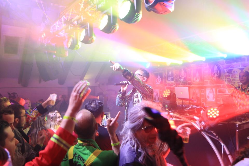 Carnavalsavond met live optreden en feestende bezoekers in Harmelen, gemeente Woerden, Groene Hart, uitbundige sfeer met kleurrijke verlichting, verklede mensen en artiest op het podium tijdens het carnaval.