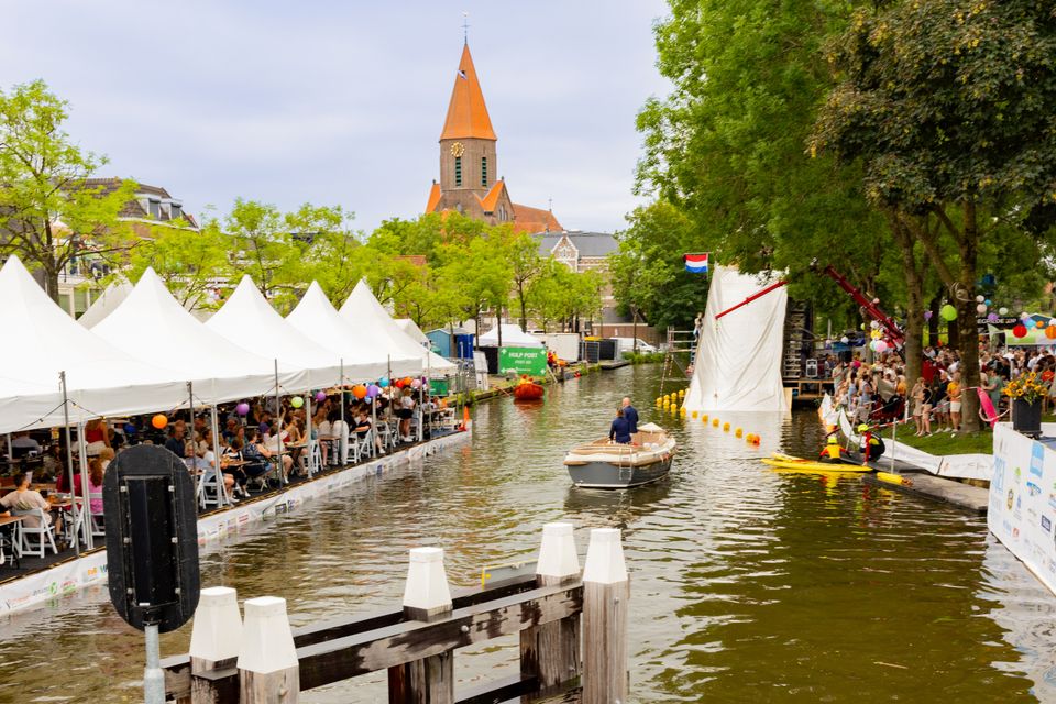 Evenement IJsselweekend in Montfoort, Groene Hart, zomers waterfestival met activiteiten en boten op de Hollandse IJssel, publiek langs de kade en feesttenten met horeca en muziek.