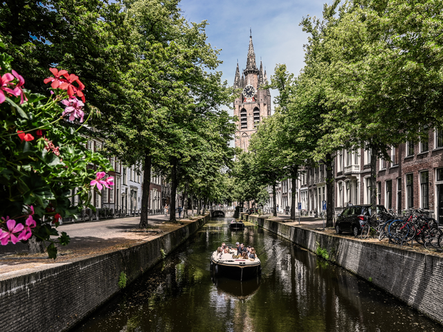 Zomerse dag in Delft met een bootje op de grachten en uitzicht op de Oude Kerk