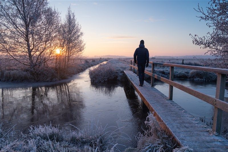 Wandelaar over een smal bruggetje tijdens de winter
