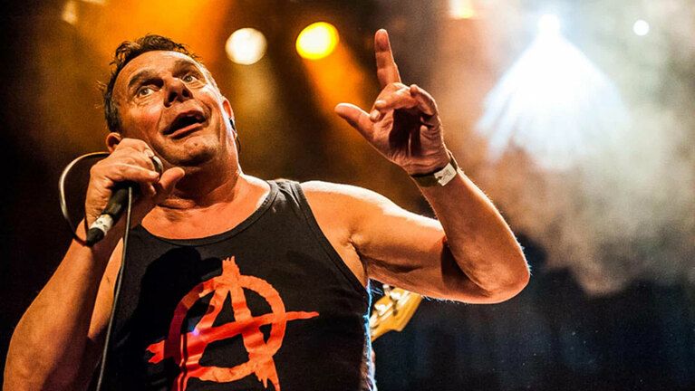 Poppodium RieTheater Woerden, Mark Foggo, Woerden, Groene Hart, energiek liveconcert waarbij de zanger met microfoon op het podium staat onder warme podiumverlichting tijdens een ska-punk optreden.