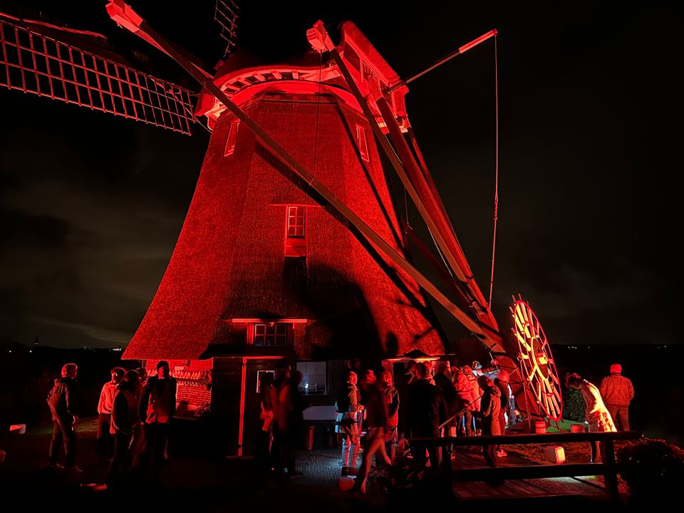 In het rood belichte Waterloosmolen tijdens molennacht van dichtbij in Rijpwetering