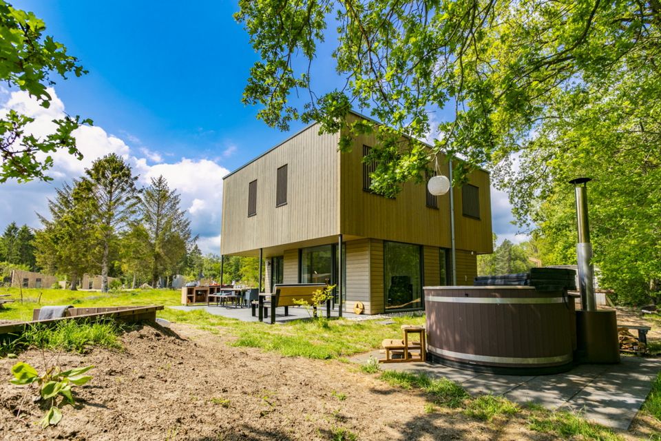 Een vakantiehuisje met hottub op een groen vakantiepark.