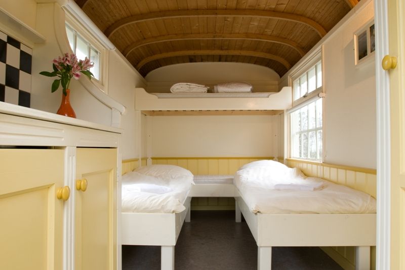 Sfeervol interieur van een Veldhuysje bij Kameryck met twee bedden, een hoogslaper en houten gebogen plafond.