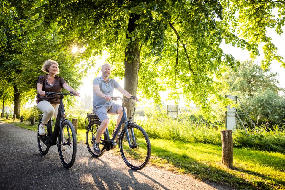 Een man en een vrouw fietsen door het polderlandschap.