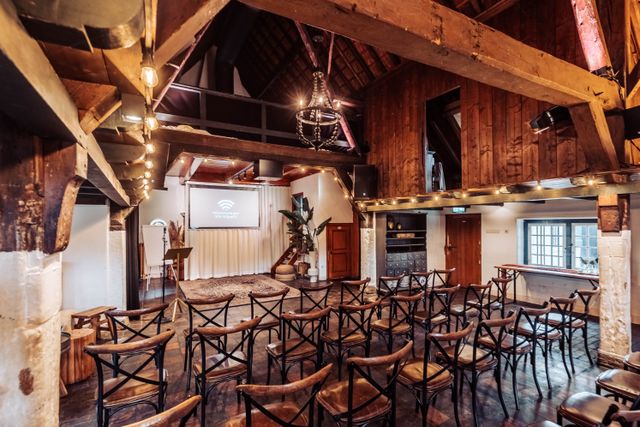 Evenementenlocatie De Willemshoeve in Woerden, Groene Hart. Zaalopstelling met stoelen gericht op presentatiescherm voor vergadering, seminar of zakelijke bijeenkomst in karakteristieke boerderijlocatie.