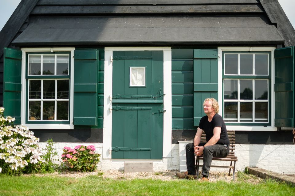 De Molenaar zit op een stoel voor de molen