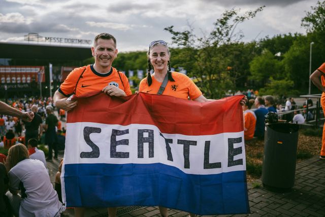 WK Voetbal: oranje fans houden Nederlandse vlag omhoog met daarop het woord Seattle geschreven