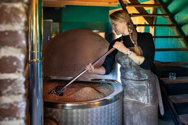 Laetitia roert in een vat met graanmout bij The Chamberick Distillery – ambachtelijke stokerij in de Utrecht Region.