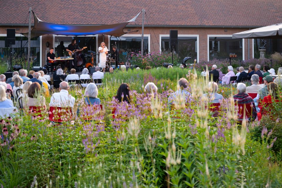Publiek bekijkt theatervoorstelling in de museumtuin van Singer Laren.