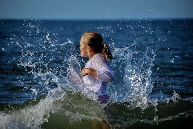 meisje met wit shirt in zee met opspattend water