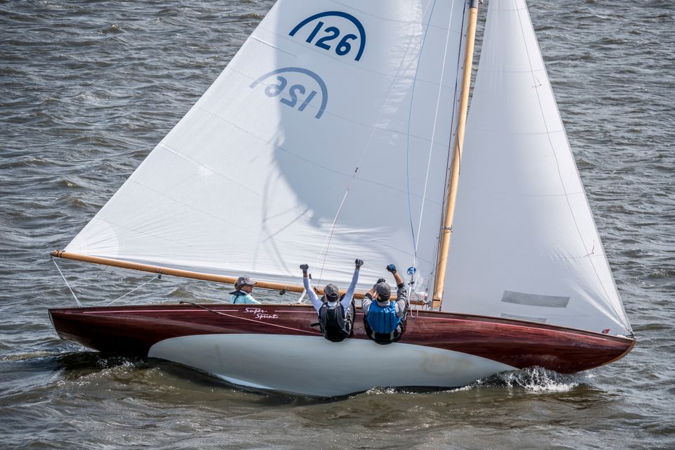 twee mannen hangen over de rand van een zeilboot