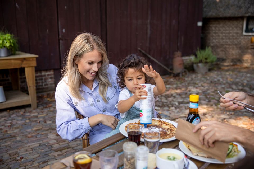 Moeder en dochter zitten op het terras een pannenkoek te eten.