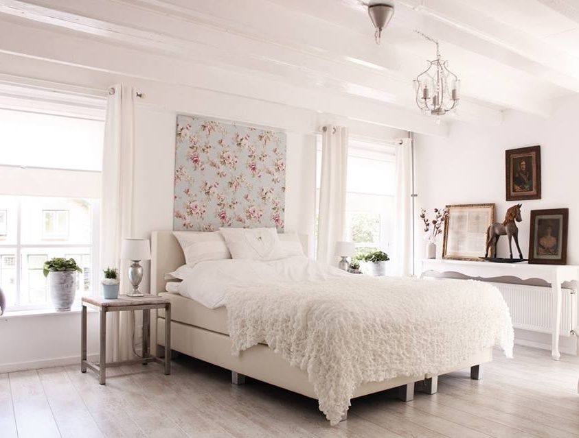 Een hotelkamer met een tweepersoonsbed, nachtkastje en kunst aan de muur.