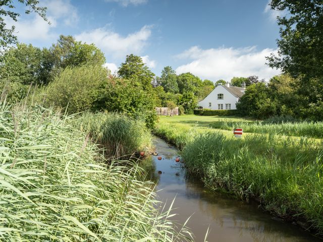 De Dommel omringt door groen en een wit huis.