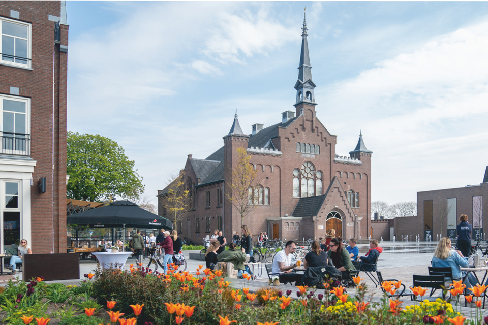 Mensen genieten op een terras in het centrum van Hoogeveen tegenover de grote kerk.