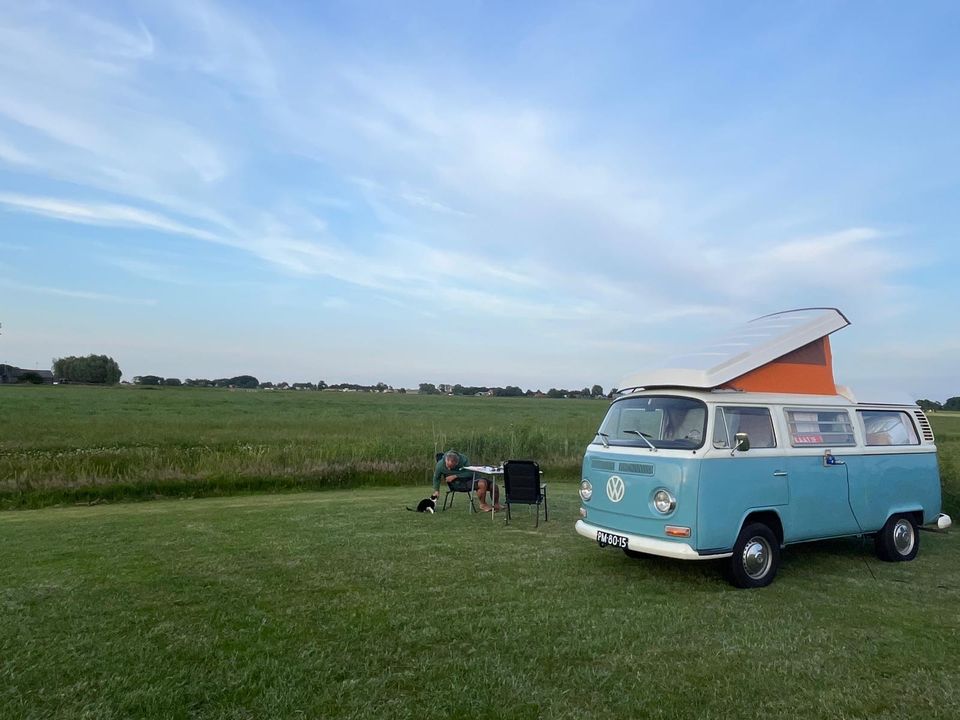 Een iconisch Volkswagenbusje op een ruime kampeerplek met uitzicht over het Friese landschap.