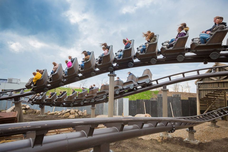 Eine Achterbahn, auf der zwei Züge mit Menschen fahren