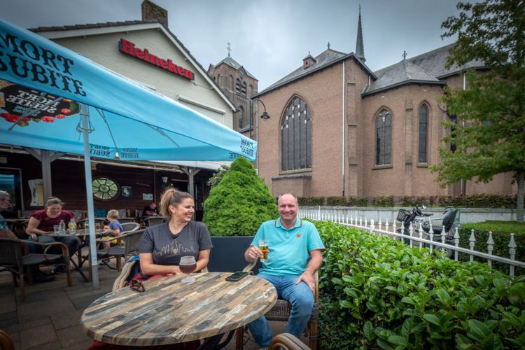 Man en vrouw op het terras van Café Kerkzicht met de kerk op de achtergrond