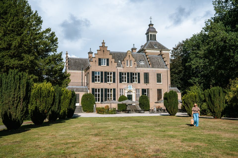 Vrouw loopt op gras voor Maarten Maartenshuis bij Landgoed Zonheuvel op De Utrechtse Heuvelrug