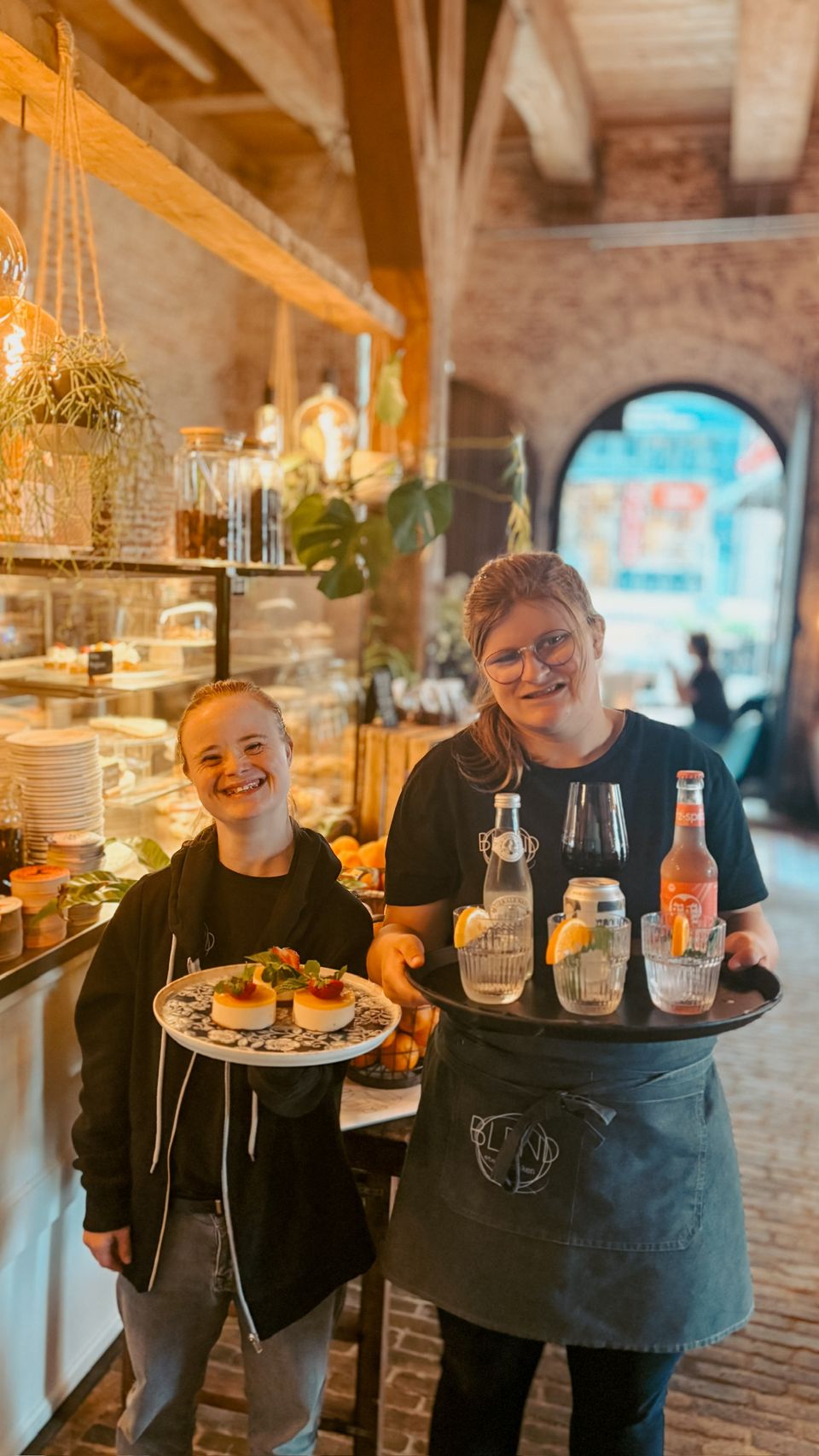 Twee mensen poseren met een vol dienblad in hun hand bij Blend in Bolsward.