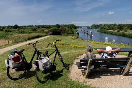 Fietsers pauzeren op bankje en kijken uit over Steenbergsche Vliet