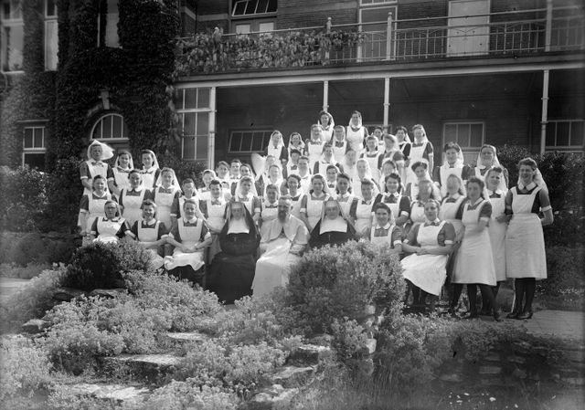 Groep verpleegsters met directie en missionaris in de tuin van psychiatrisch ziekenhuis Coudewater