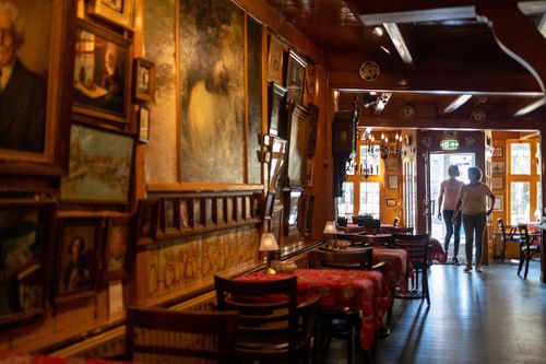 Twee dames lopen Hotel Spaander in en zien de kunstcollectie aan de muur hangen.