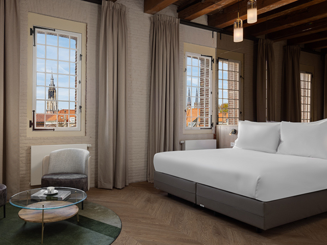 Een kamer binnen Westcord Hotel Delft met een tweepersoonsbed en zicht op de Nieuwe Kerk
