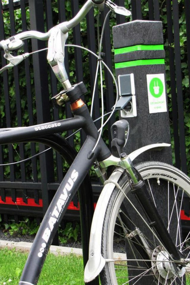 Een e-bike is met een stekker gekoppeld aan een e-bike oplaadpunt.