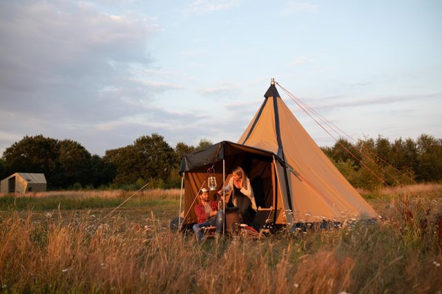 Een stel zit voor hun tipitent in de natuur.